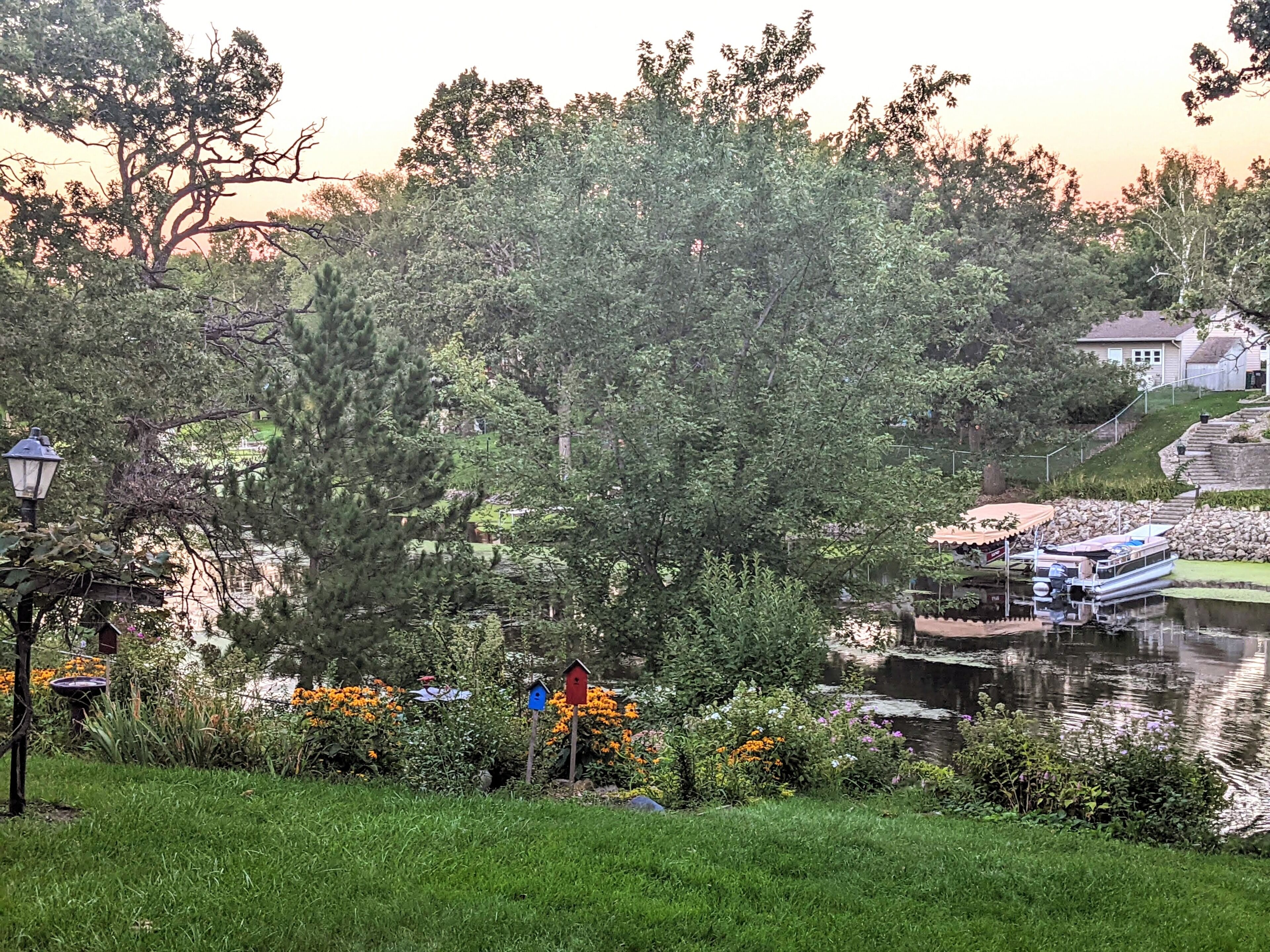 A serene lakeside setting with a dock, boats, and a gazebo.