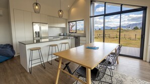 A modern kitchen with a large island, bar stools, and a dining table with chairs. - Southern Stars - FREE WiFi (Twizel)