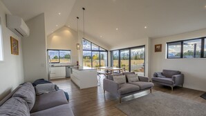 A spacious living area with a sofa, a grey armchair, and a dining table. - Southern Stars - FREE WiFi (Twizel)