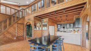 A spacious kitchen with wooden beams, a central island, and a dining area with blue chairs. - Lake Travis Gem, Golf, boat, Tennis, Pool (Point Venture)