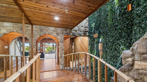 A wooden staircase with a rope railing leading to a stone wall covered in ivy. - Lake Travis Gem, Golf, boat, Tennis, Pool (Point Venture)