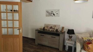 Ett rum med en dörr av trä, ett litet bord med dekorativa föremål, en tavla som hänger på väggen och en lampa.