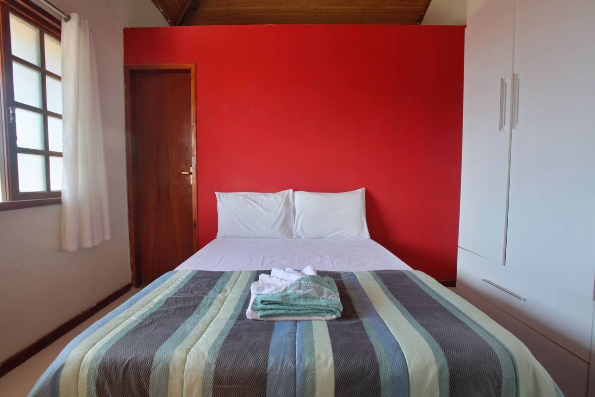 A bed with white linens, a striped bedspread, and a folded towel on the bed.