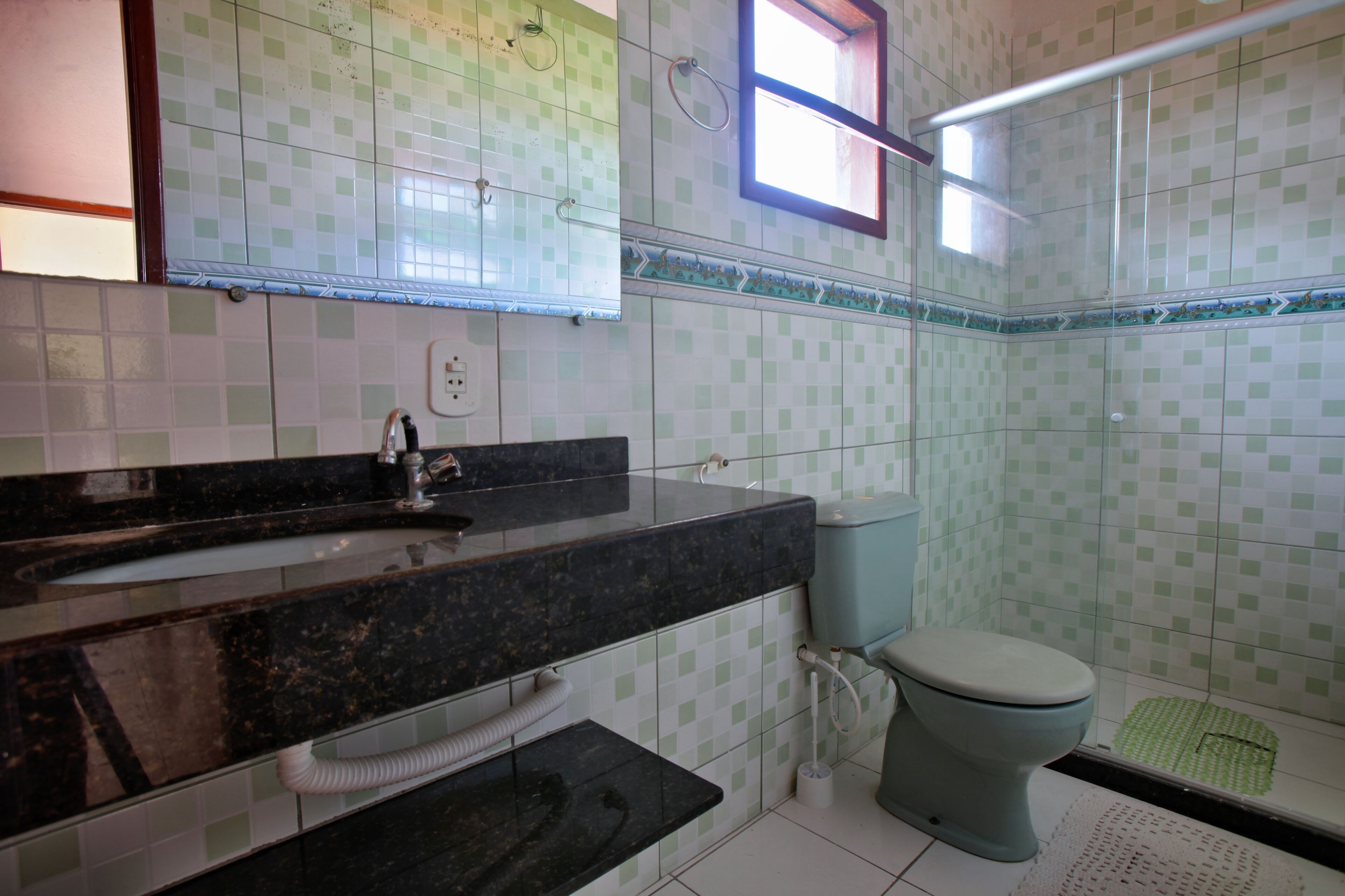 A bathroom with a black marble sink, a toilet, and a shower area.
