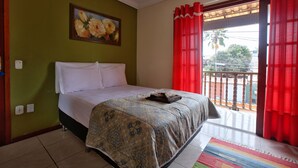 A bedroom with a bed, a painting on the wall, and a balcony with red curtains. - Suíte Palmeiras  (Cabo Frio)