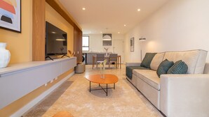 A modern living room with a sofa, coffee table, and a kitchen area in the background. - Tabas | Moderno apto em Ipanema - RJ | IP0019 (Rio de Janeiro)