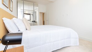 A modern bedroom with a large bed, a bedside lamp, and a mirror. - Tabas | Moderno apto em Ipanema - RJ | IP0019 (Rio de Janeiro)