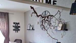 A cozy living room with a wooden dining table, a comfortable armchair, and a decorative wall piece above the table. - Vacation apartment "Bergliebe"  (Germaringen)