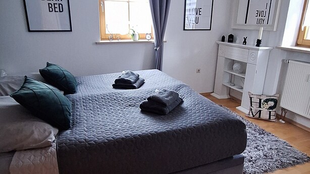 A modern bedroom with a large bed, a chandelier, and framed pictures on the walls. - Vacation apartment "Bergliebe"  (Germaringen)