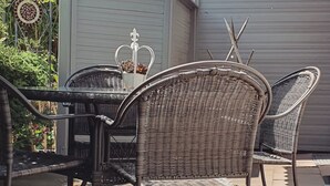 A patio area with wicker furniture, including a table and chairs, and a decorative metal sign. - Vacation apartment "Bergliebe"  (Germaringen)