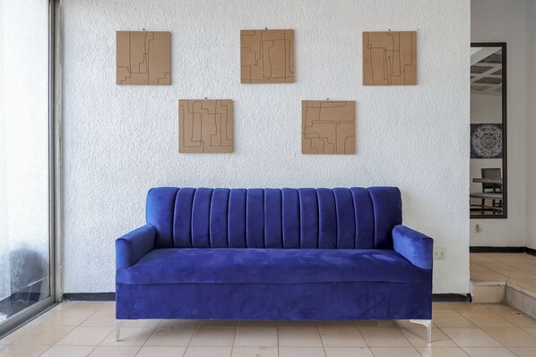 A blue sofa in a room with a white textured wall and a large window.