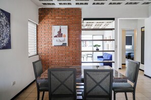 A dining area with a brick accent wall, a glass table, and modern chairs.
