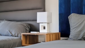 Ett modernt sovrum med en säng, ett sängbord med en lampa och ett litet bord vid sängen.