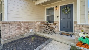 A house with a front porch, a door with a wreath, a small table and chairs, and a welcome mat. - Relaxing 3BR w/ Waffle Bar•Lackland BMT•Seaworld (San Antonio)