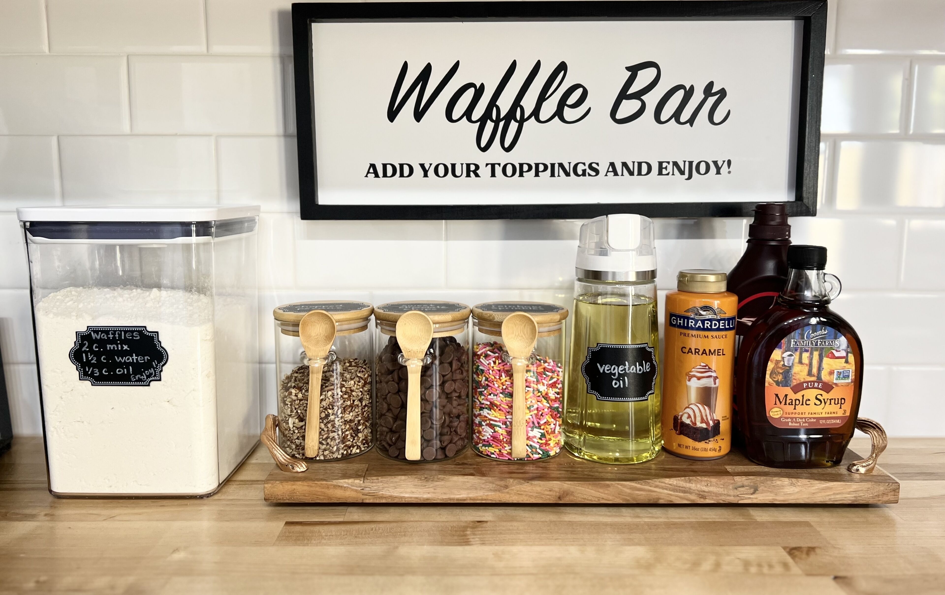 Un bancone della cucina con un cartello che indica una waffle bar, ingredienti per waffle e diversi condimenti.