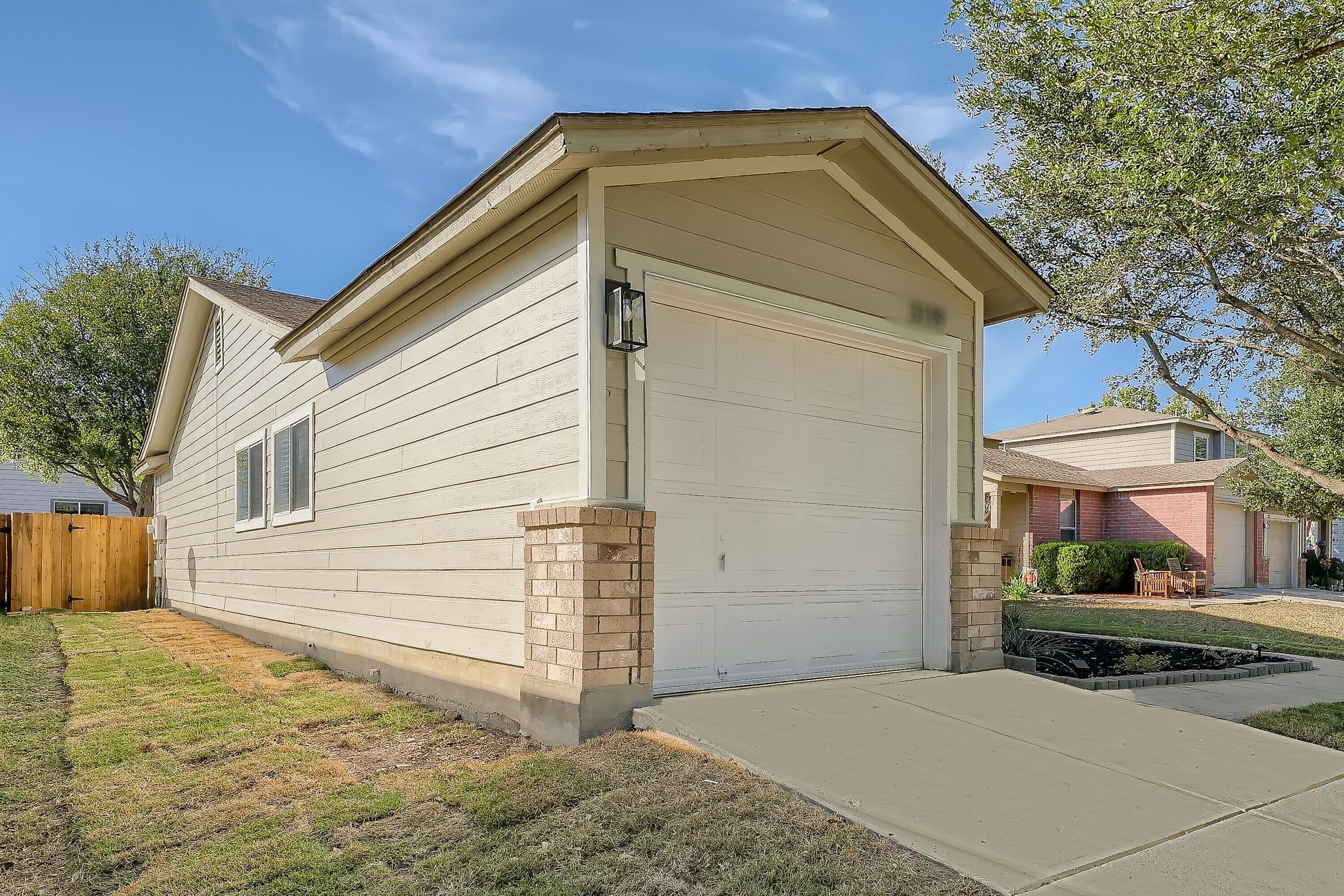 A single-story house with a garage, a brick foundation, and a small front yard.