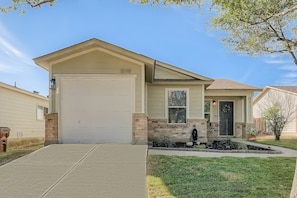 A single-story house with a garage, a front porch, and a small garden area. - Relaxing 3BR w/ Waffle Bar•Lackland BMT•Seaworld! (San Antonio)