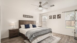 A bedroom with a bed, nightstand, ceiling fan, and a window with blinds. - Relaxing 3BR w/ Waffle Bar•Lackland BMT•Seaworld (San Antonio)