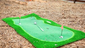 A miniature golf course with three holes, surrounded by mulch.