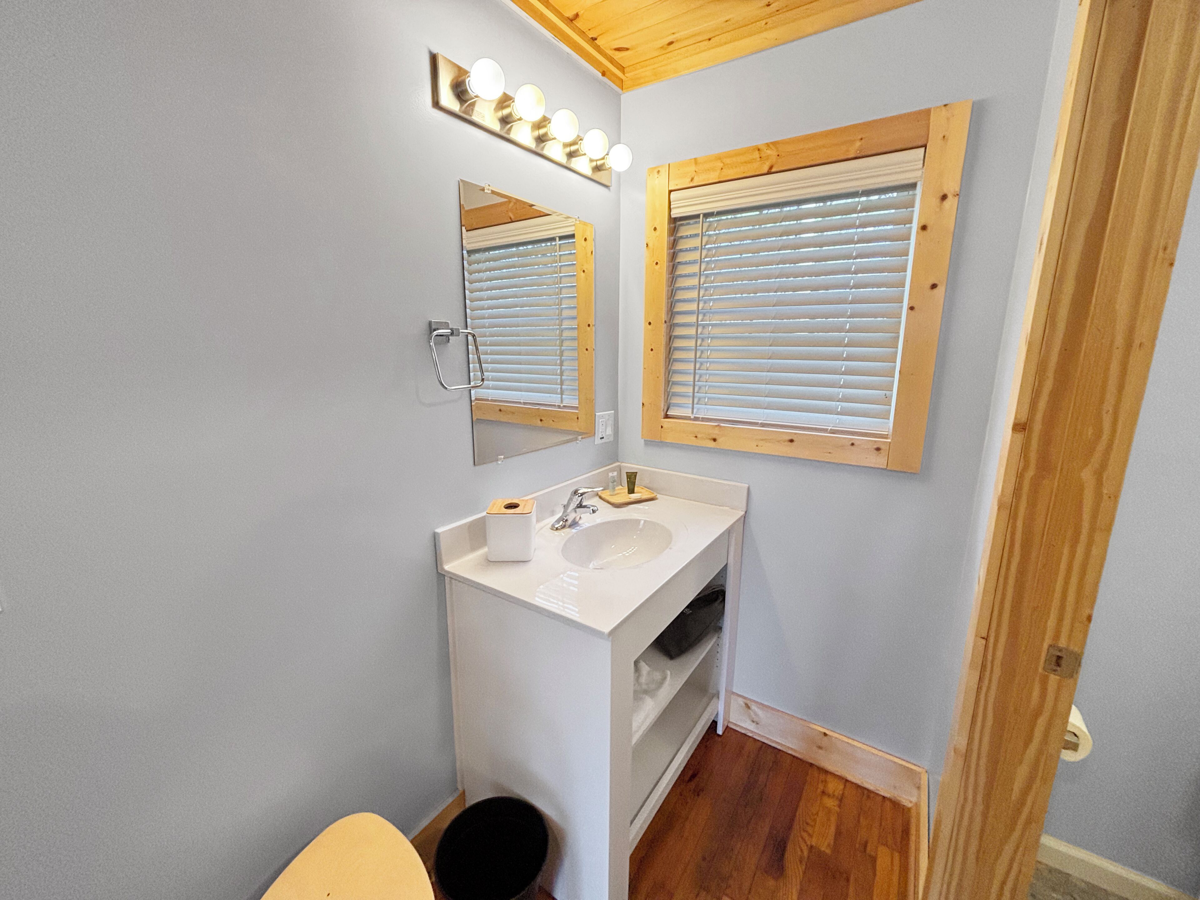 A bathroom with a white sink, mirror, and wooden blinds.