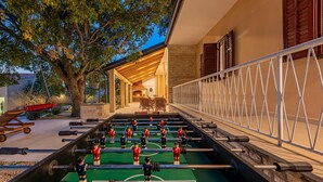 A foosball table set up outdoors with a patio area, a tree, and a building in the background. - Holiday Home Apios - Three Bedroom Holiday Home with Swimming Pool (Benkovac)
