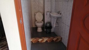 Ein kleines Badezimmer mit Toilette, Waschbecken und Mülleimer.