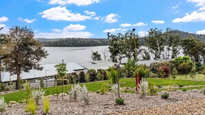 A residential area with a view of a lake, houses with sloped roofs, and a variety of vegetation including trees and shrubs. - Piccolo Segreto Lake Conjola (Lake Conjola)
