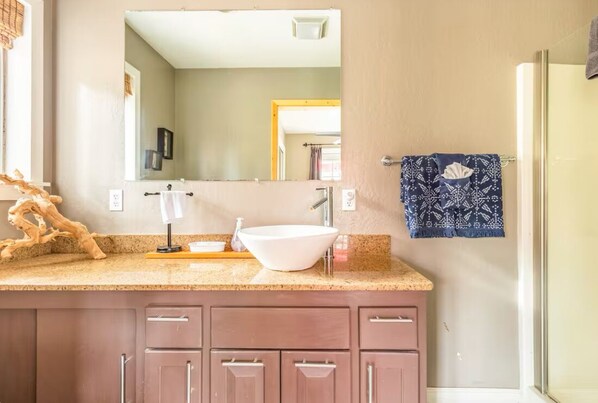 A bathroom with a beige wall, a white sink, a mirror, and a towel rack with a blue towel.