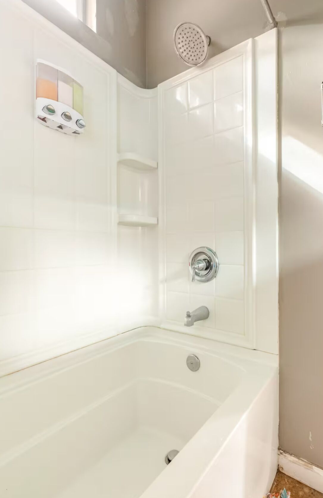 A modern bathroom with a freestanding bathtub, a handheld showerhead, and a wall-mounted faucet.