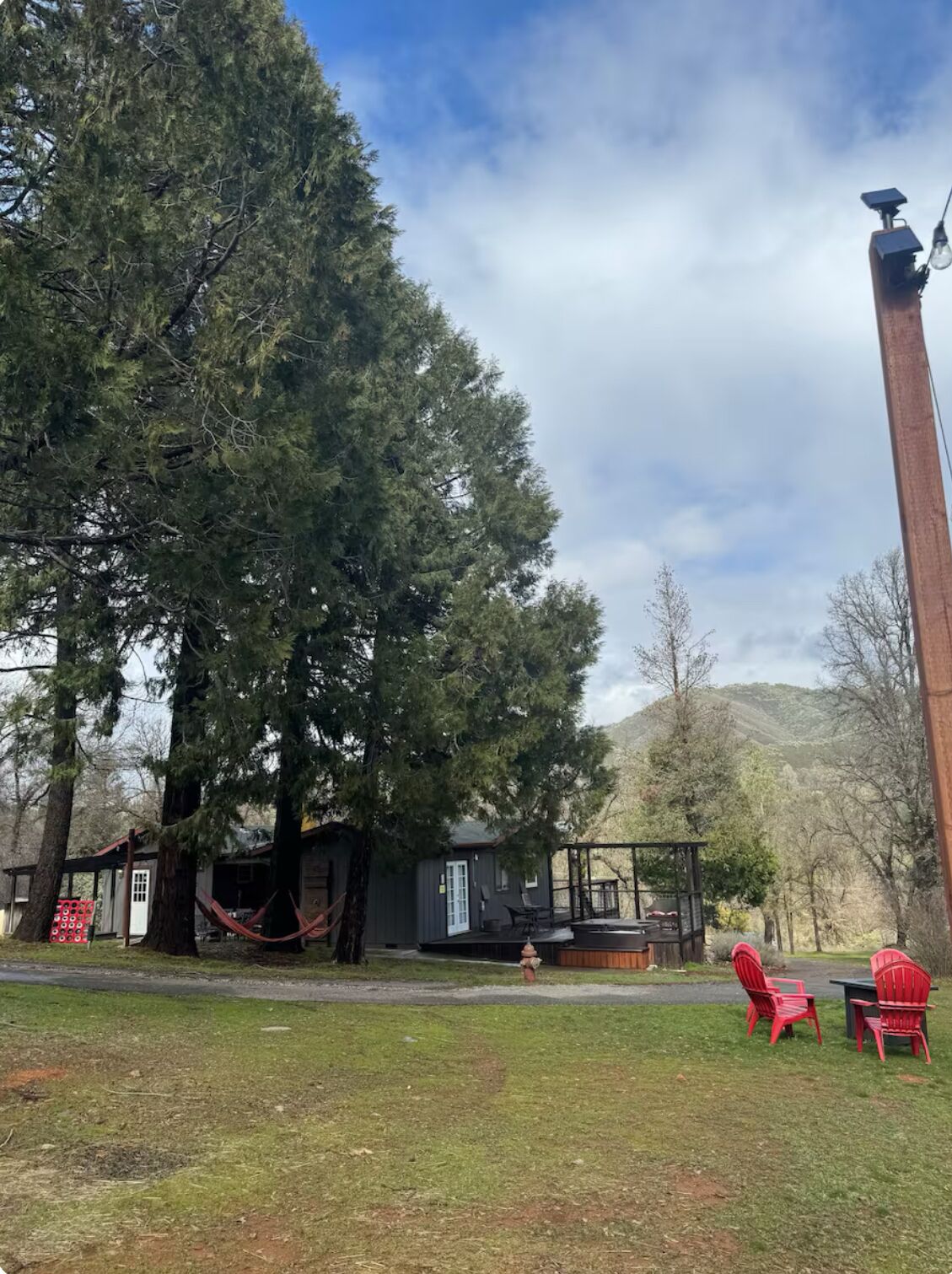 Una baita rustica con una veranda, circondata da alberi e con vista su una montagna.