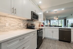 A modern kitchen with white cabinetry, a black stove, and a built-in microwave.