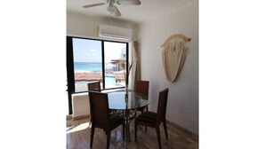 Ein Essbereich mit Glastisch und Stühlen, einem Deckenventilator und Blick auf Strand und Pool.