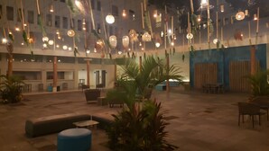 Une cour intérieure agrémentée de guirlandes lumineuses, de coins salon et de plantes en pot.
