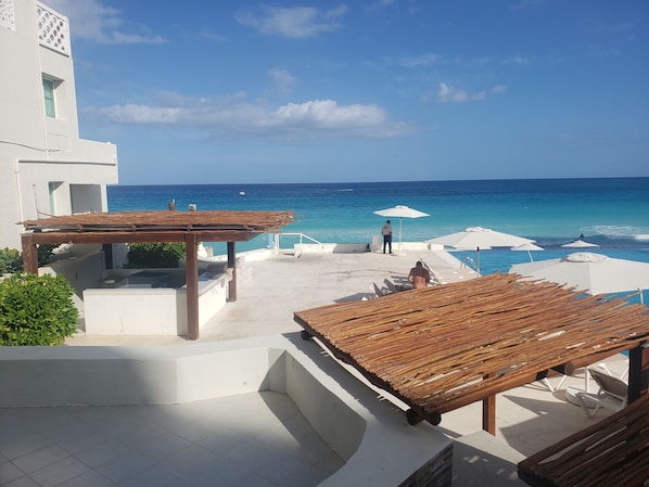 A resort with a pool area, wooden pergolas, and a view of the ocean. - Beachfront with amazing view (Cancún)