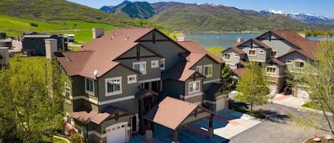 Un edifici d'apartaments de diversos pisos, amb garatge, envoltat de vegetació i vistes al llac.
