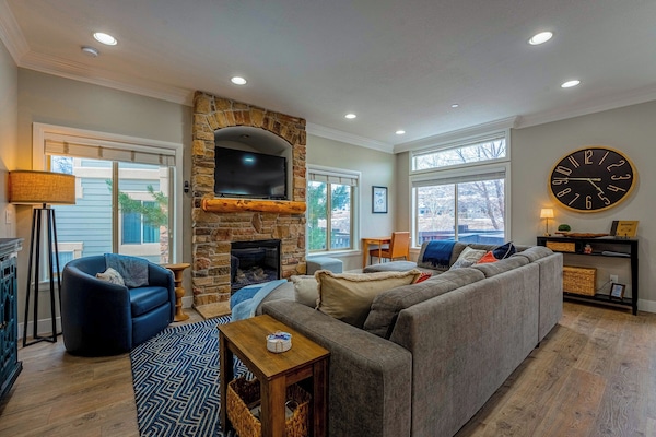 A stone fireplace with comfy seating and smart tv for family movie night.