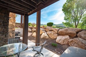 Eine Terrasse im Freien mit Steinmauern, einem Grill und einem Glastisch.