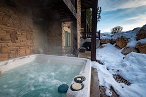 Ein Steingebäude mit Whirlpool, umgeben von Schnee und Felsen.