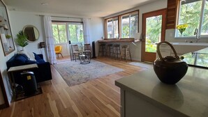 Una cocina moderna con un ventanal grande, suelo de madera y un comedor con taburetes de bar.