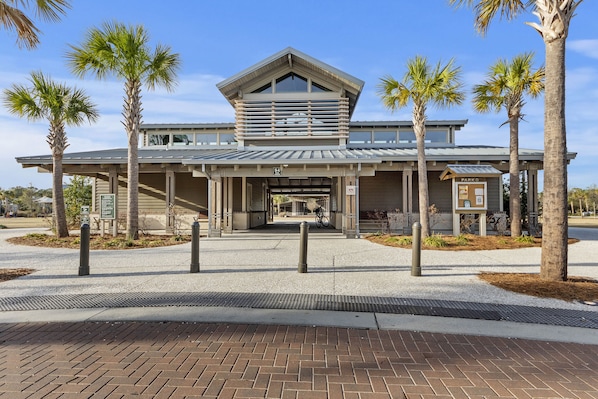 A modern building with a covered entrance, palm trees, and a bike parked outside. - Updated Condo w/ Pool, Tennis, Walk to the Beach , Coligny and Celebration Park! (Hilton Head Island)