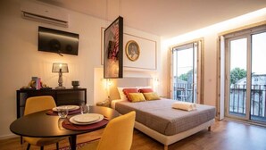 A hotel room with a bed, a dining table with chairs, a TV mounted on the wall, and a balcony with a view. - Lemago Poveiros Apartments (Porto)