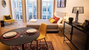 A modern apartment with a dining area, a sofa, a bed, and large windows. - Lemago Poveiros Apartments (Porto)