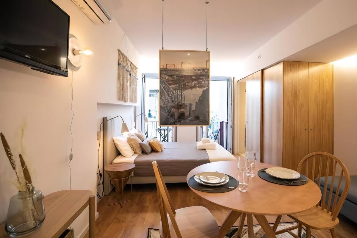 A modern, compact living space with a sofa, dining table, and a large window.