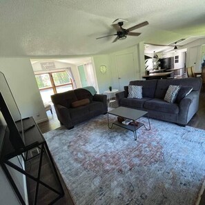 A living room with a grey sofa, a coffee table, and a ceiling fan.