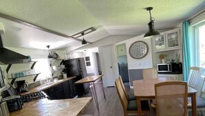 Uma cozinha moderna com ilha central, banquetas e uma mesa de jantar com cadeiras.