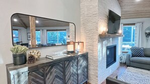 A modern living room with a herringbone-patterned cabinet, a fireplace, a large mirror, and a cozy seating area. - Echo Summit Cabin: Hot Tub, 1mi to Sierra at Tahoe (Twin Bridges)