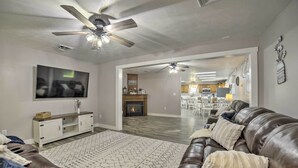 A spacious living room with a leather sofa, a flat-screen TV, a fireplace, and a ceiling fan. - Near Mines & Meadows: Spacious Home w/ Game Room (Beaver Falls)