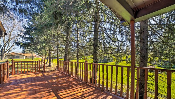 A wooden deck with a railing, surrounded by tall trees and a grassy area. - Near Mines & Meadows: Spacious Home w/ Game Room (Beaver Falls)