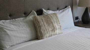 A bed with a tufted headboard, white bedding, and a lamp on the side.