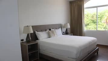 Una cama bien tendida con un cabecero de madera, dos lámparas de noche y una mesita de noche con lámpara.